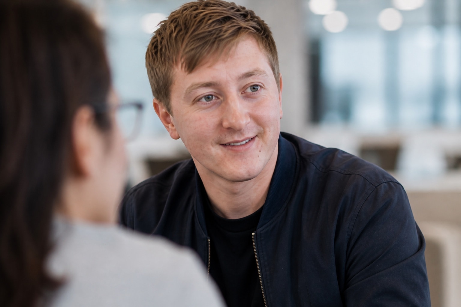 Moritz Zinecker lächelt in einem nah aufgenommenen Gespräch im Büro