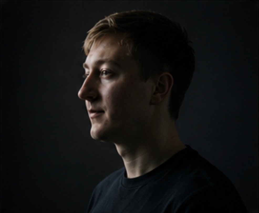 Seitliches Studio-Porträt von Moritz Zinecker vor dunklem Hintergrund