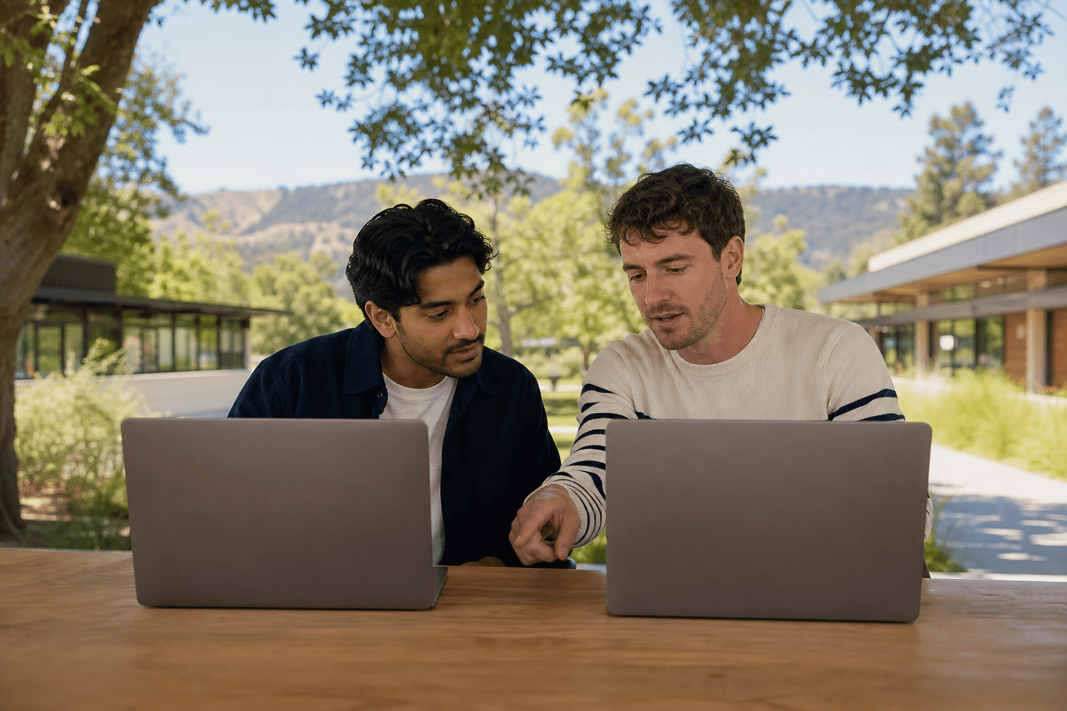 Drei Menschen arbeiten gemeinsam an Laptops im Freien